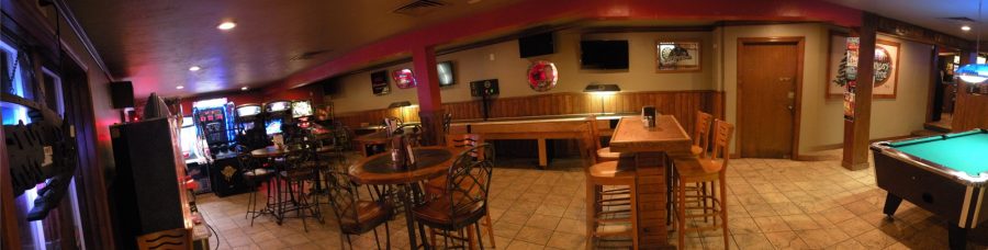 The game room at Wouters' Front with a shuffleboard table, pool table, dartboards, arcade cabinets and high-top tables